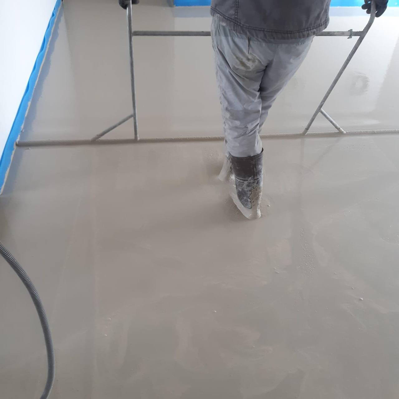 Ouvrier bottes dans chape fraîche